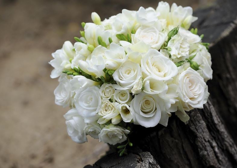 Soft white roses and buds arranged in a bouquet on wood, funeral homes Reserve, LA