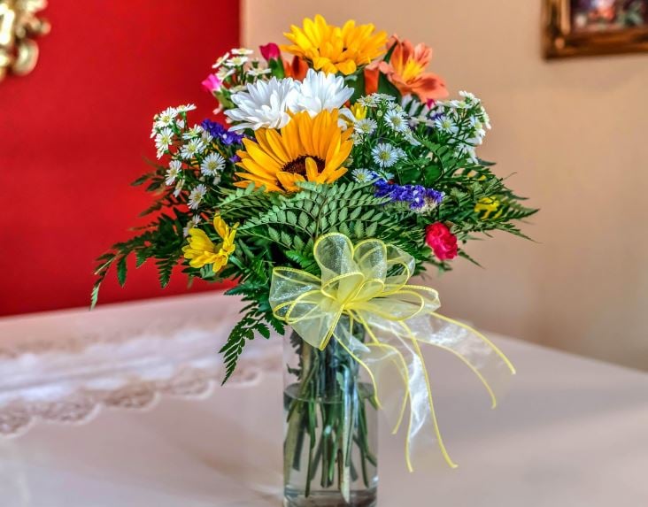 Sunflowers and daisies in vase with ribbon, symbol of care, funeral homes Reserve, LA